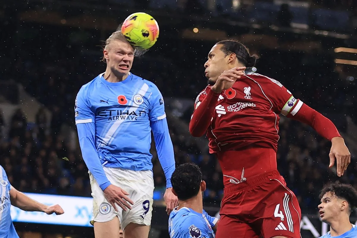 Erling Haaland of Manchester City heads the ball away from a corner watched by Virgil van Dijk of Liverpool during the Premier League match between Manchester City and Liverpool at Etihad Stadium